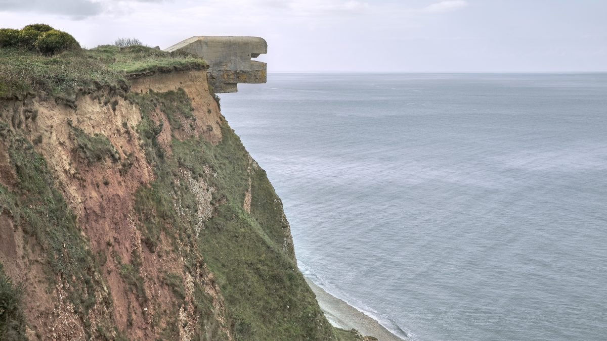 Steilküste am Meer, von der Klippe ragt ein Objekt aus Beton hervor