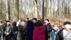 Eine Gruppe Kinder steht mit verbundenen Augen in einem Wald