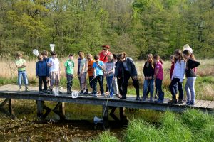 Kinder stehen auf einer Brücke über einen Teich